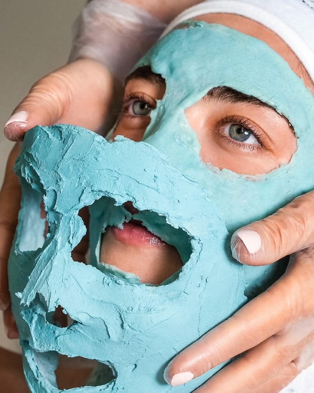 Hands meticulously peeling away the solidified cooling mask